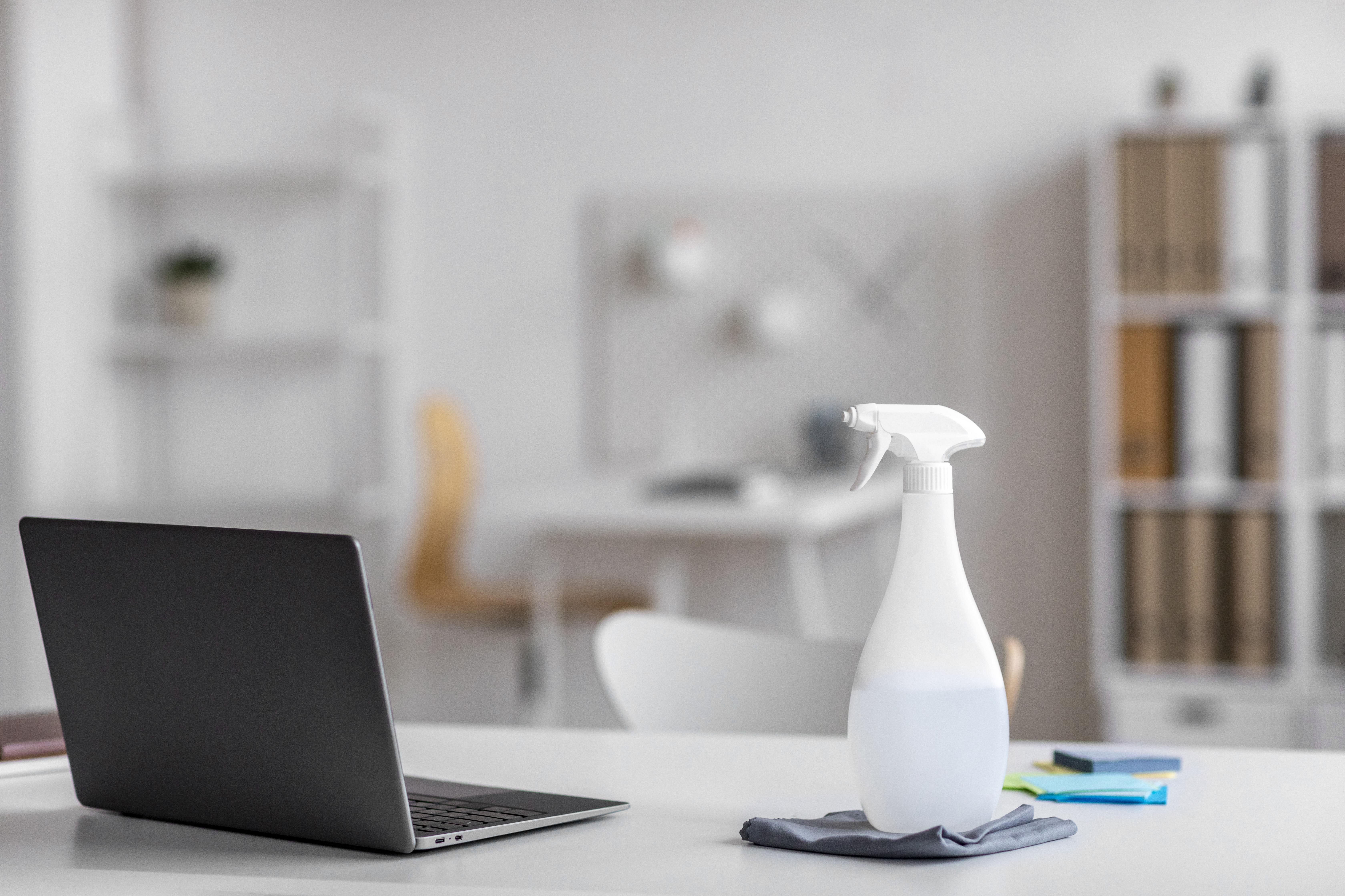Office desk being disinfected by a commercial cleaning service professional